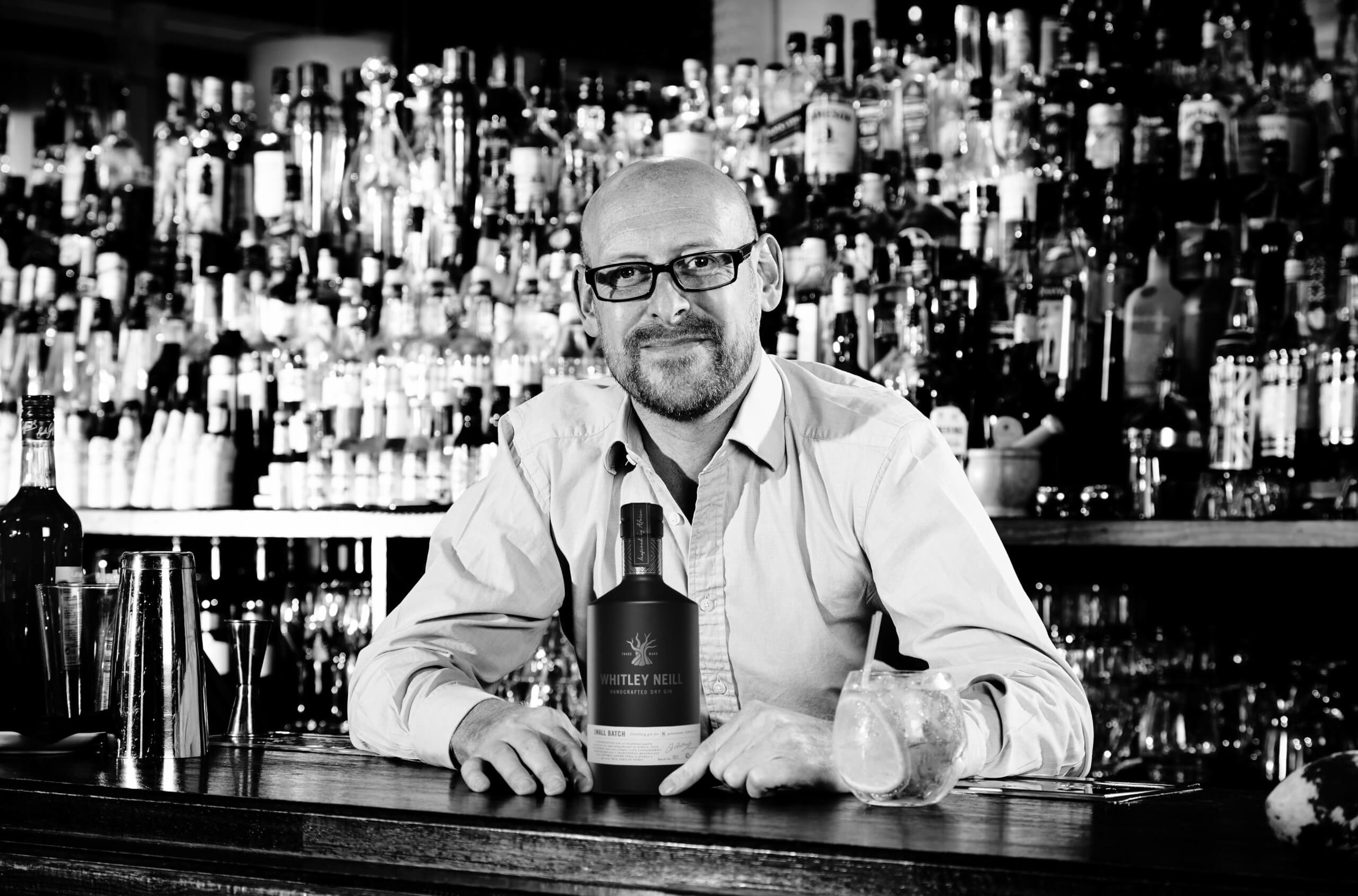 JohnnyNeillbehindBarwithbottleandGTrocks Johnny Neill Interview whitley neill gin distiller